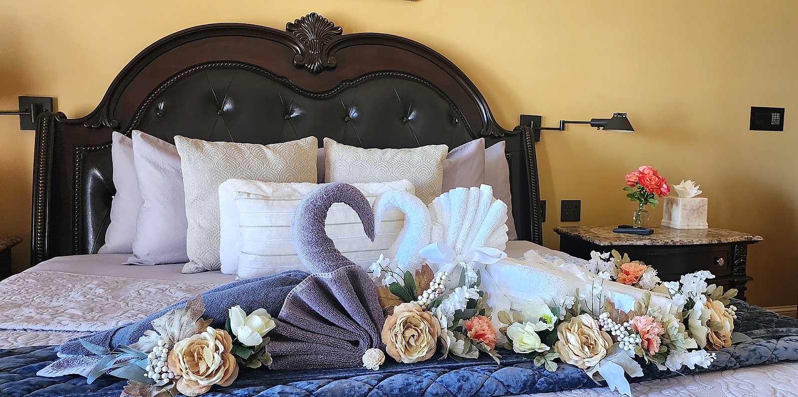Guest suite bed decorated with towel swans and flowers